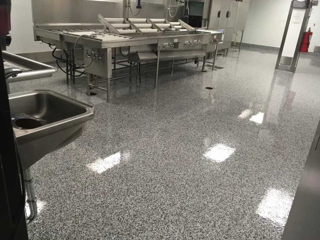 Glossy gray flake epoxy floor in a commercial kitchen with stainless steel equipment