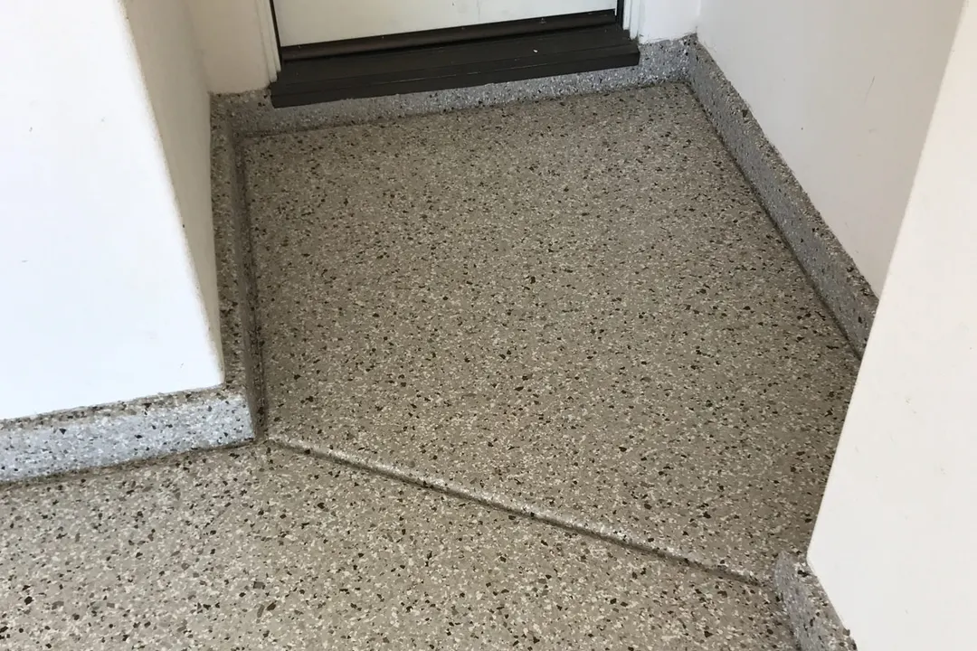 Light flake coated landing at a door opening with a saw-cut joint and a darker edge detail