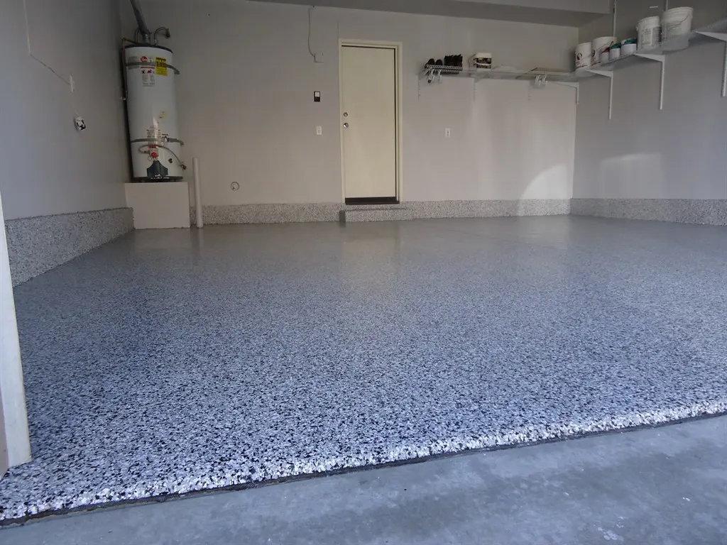 Blue and white flake garage floor with a coved edge along white walls and a water heater