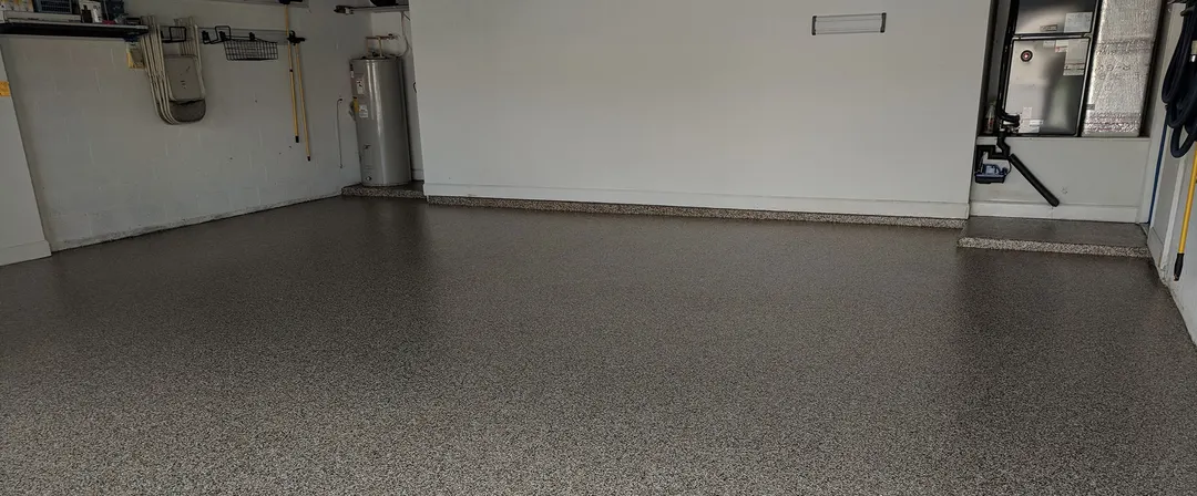 Wide view of a garage with a gray flake epoxy floor and white walls